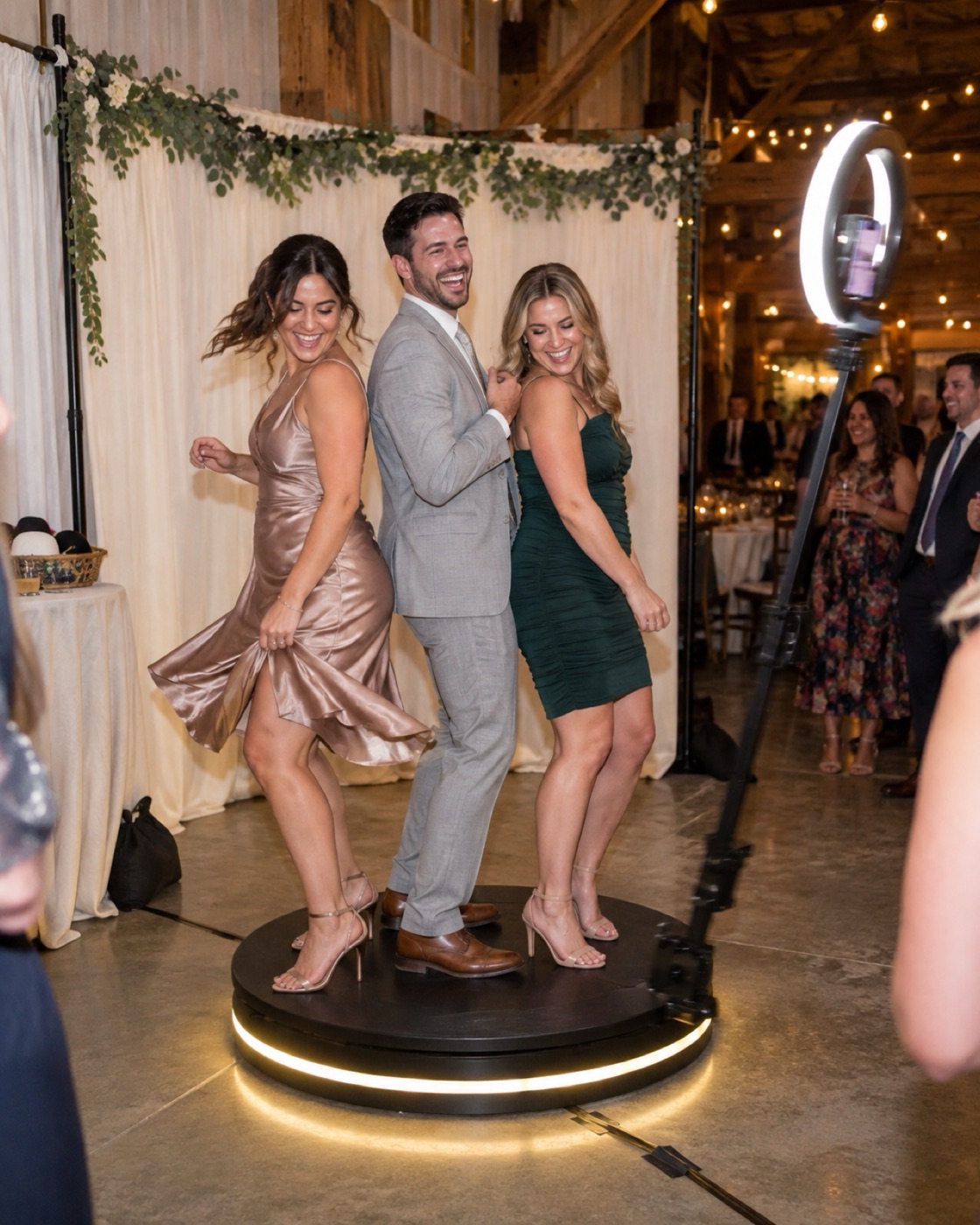 Three guests dancing on the 360 platform, set up in front of an ivory drape backdrop, as the camera arm circles them
